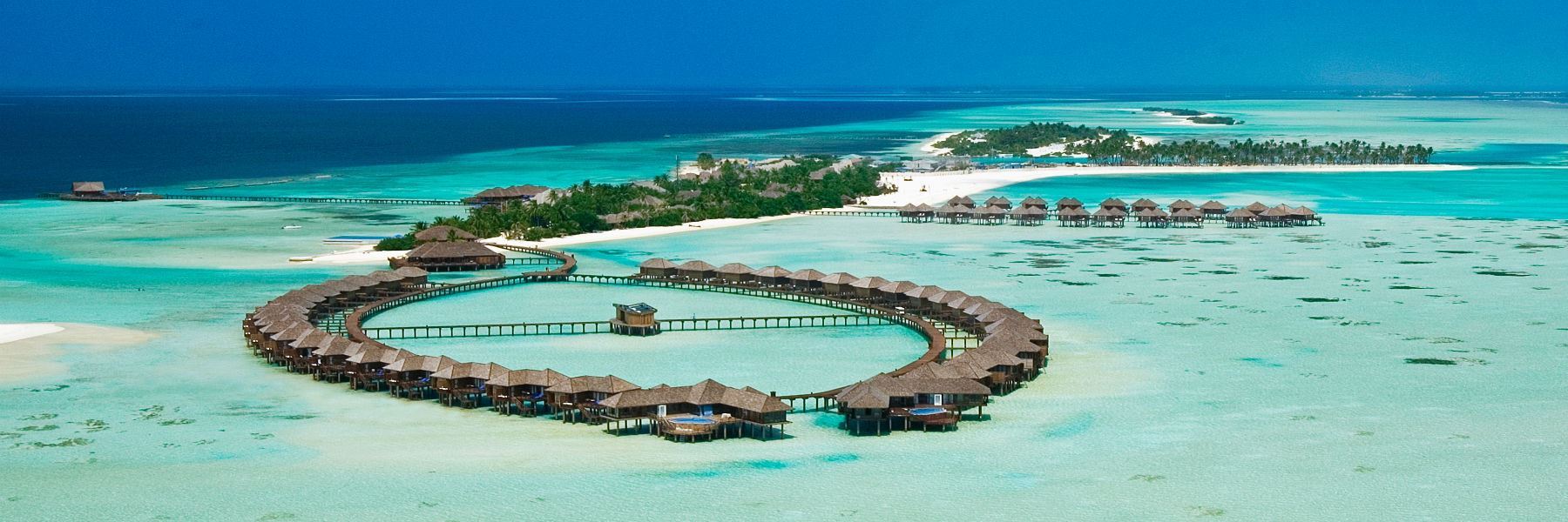 Sun Siyam Olhuveli Maldives is one of the most popular lifestyle resorts in the Maldives, offering a perfect blend of relaxation, adventure, and affordable luxury. Spread across three interconnected islands in South Malé Atoll, the resort is known as “The Paradise of Plenty” thanks to its wide range of accommodation, dining venues, activities, and entertainment options.
Surrounded by crystal-clear lagoons, white sandy beaches, and vibrant coral reefs, the resort caters to honeymooners, couples, families, and groups alike. Guests can enjoy snorkeling, diving, dolphin cruises, watersports, spa treatments, and one of the longest swimming pools in the Maldives.
The resort is especially attractive for travelers seeking a large island experience with multiple restaurants, bars, and facilities while still enjoying easy access from Malé Airport
